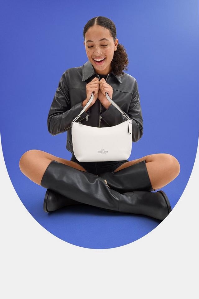 a woman sitting on the ground holding a white purse