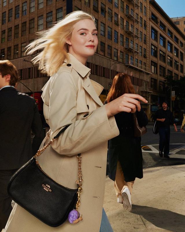 a woman in a trench coat walking down a city street